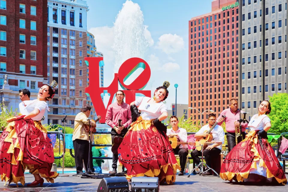 A group of Latino dancers and musicians perform in front of the Love sculpture in Philadelphia.